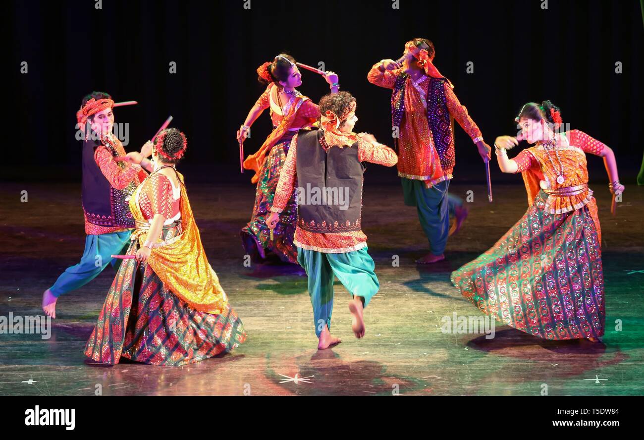 Indian group dancers perform Indian folk dance of Gujarat popularly known as the Dandiya dance or garba wearing traditional dance costumes Stock Photo
