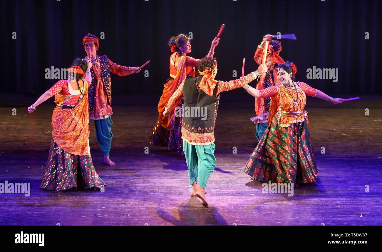 Indian group dancers perform Indian folk dance of Gujarat popularly known as the Dandiya dance or garba wearing traditional dance costumes Stock Photo