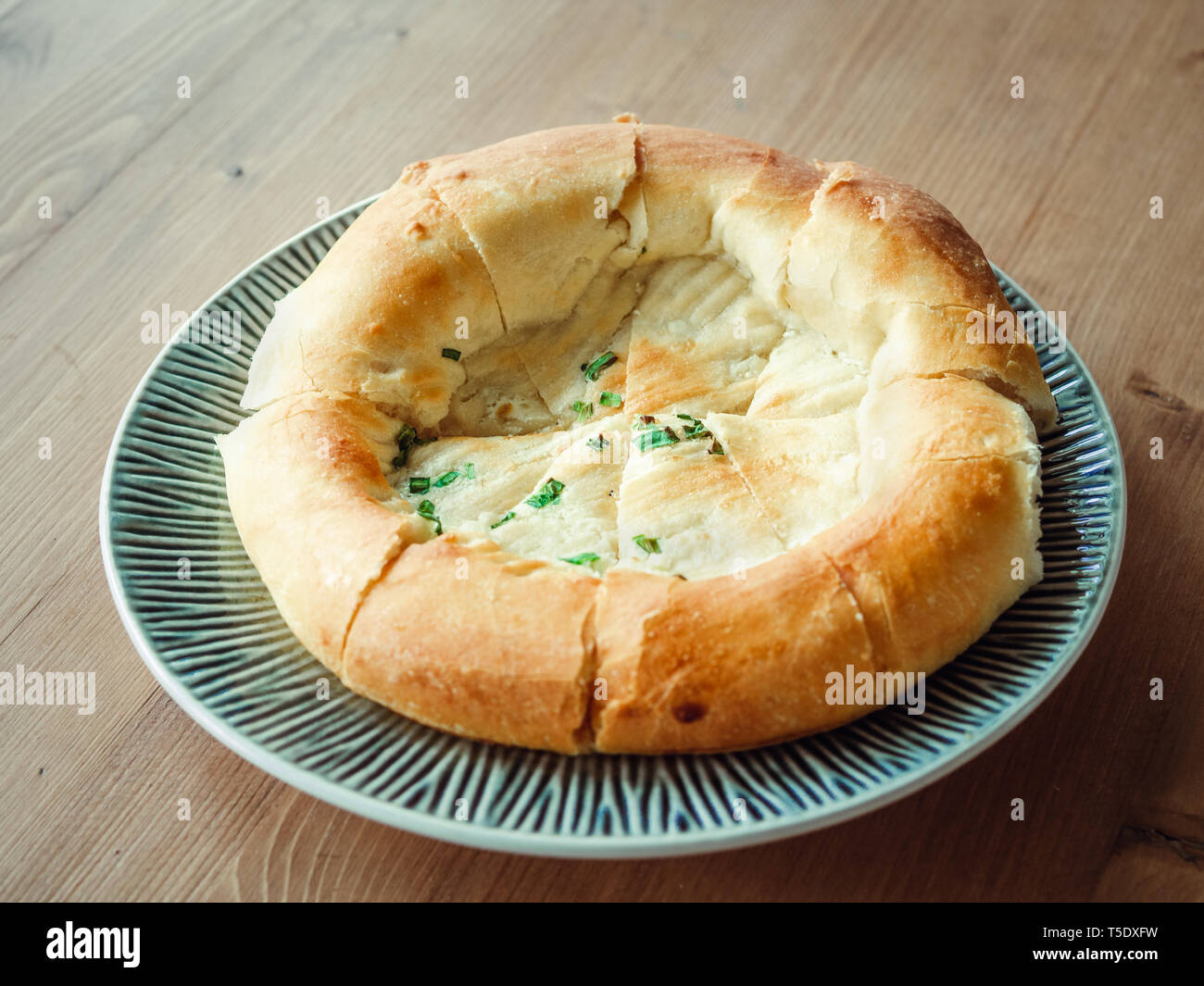 tasty tandoor baked bread on plate. National asian bread - tandoor bread with green onion on wooden table. Natural day light Stock Photo