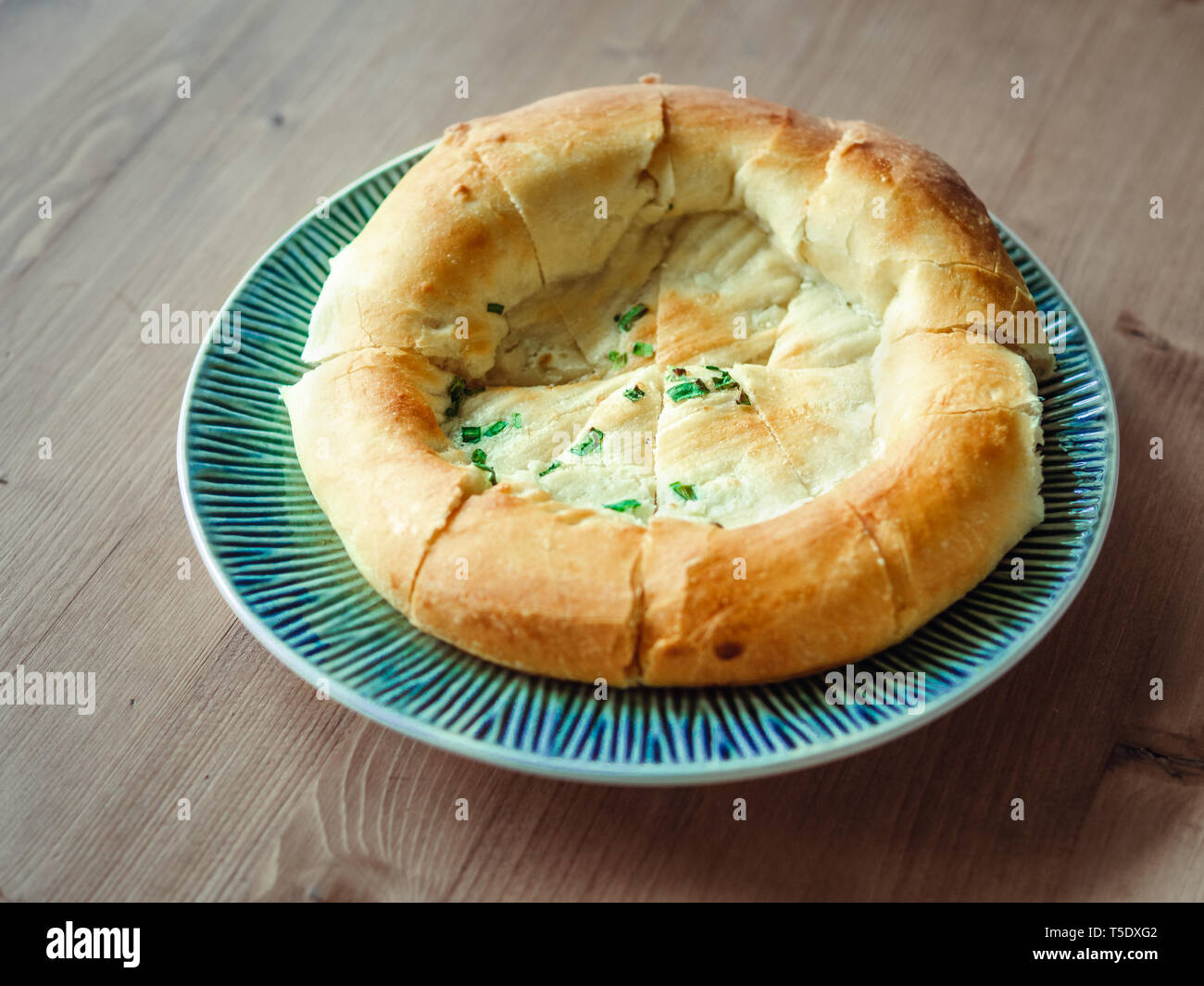 tasty tandoor baked bread on plate. National asian bread - tandoor bread with green onion on wooden table. Natural day light Stock Photo