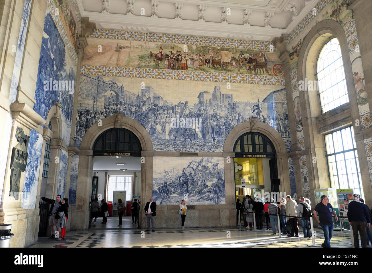 Passengers queue beneath azulejos blue tiles on walls to buy train tickets inside Sao Bento Railway Station in Porto Portugal Europe   KATHY DEWITT Stock Photo