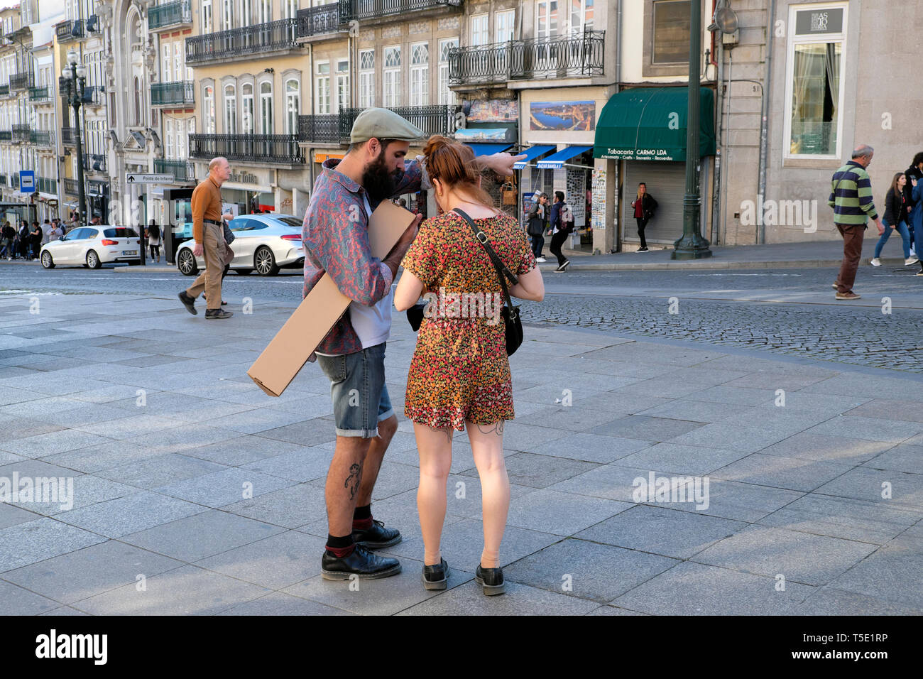 Young hipster couple man with beard standing working out directions on a street near Sao Bento railway station Porto Portugal Europe KATHY DEWITT Stock Photo