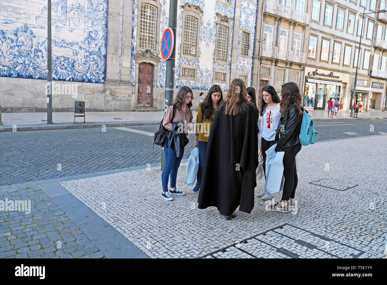 University female student in black cloak talking to friends in street Igreja do Carmo near Praça de Carlos Alberto Porto Portugal Europe KATHY DEWITT Stock Photo