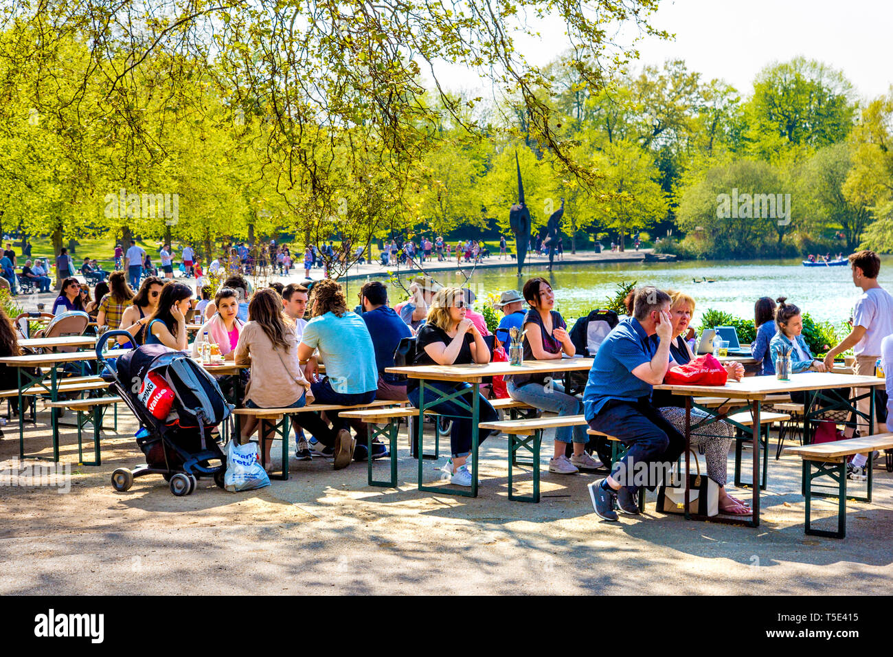 21st April 2019 - People sitting in the sun at the Pavilion Cafe by Wast Boating Lake during Bank Holiday heatwave in Victoria Park, London, UK Stock Photo