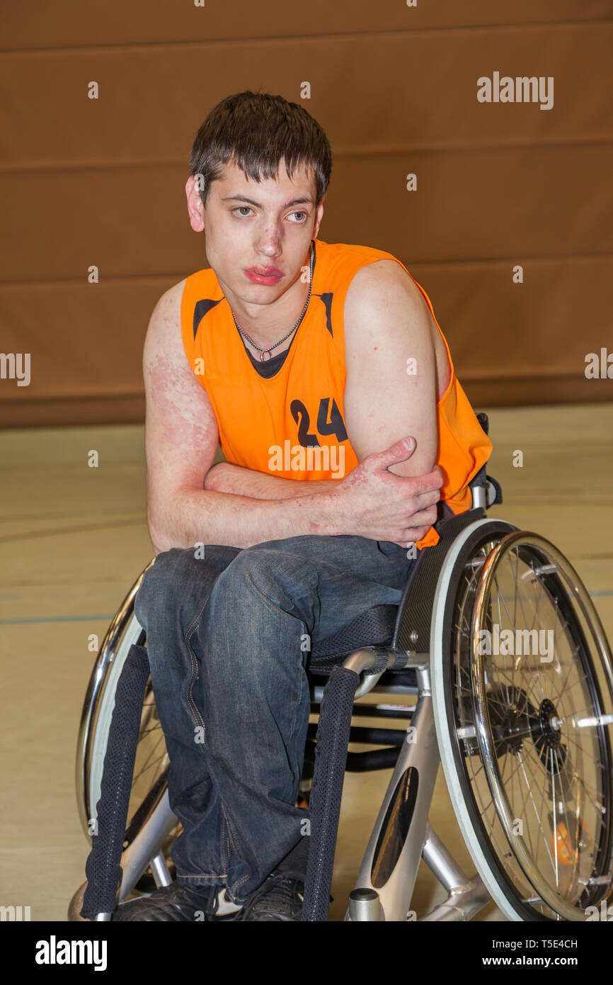 Handicapped boy with sports shirt sitting in a sports wheelchair Stock Photo