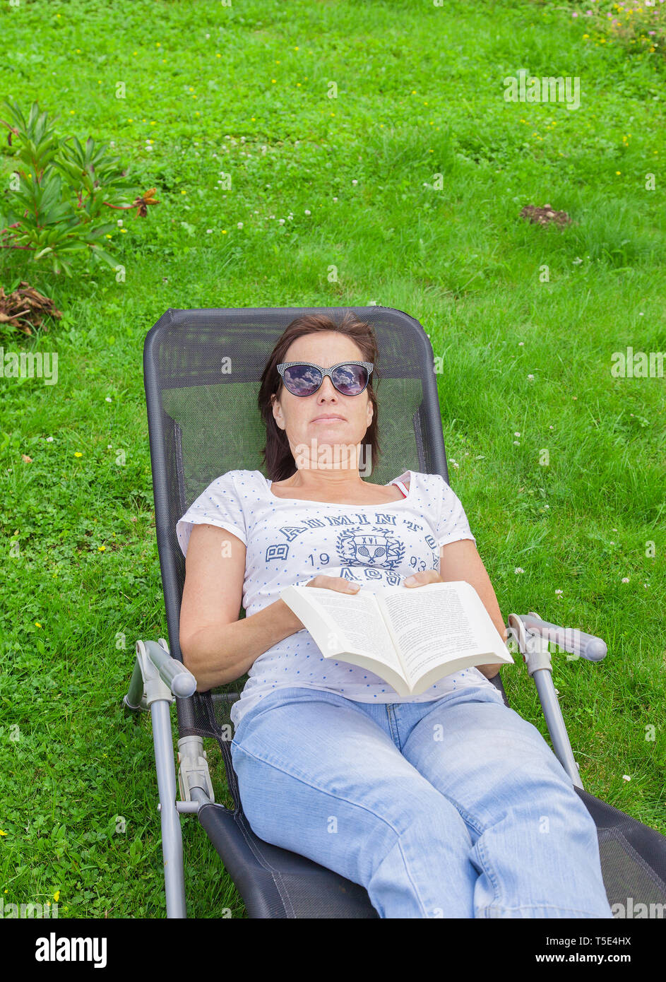 Woman reading a book in a lounger Stock Photo