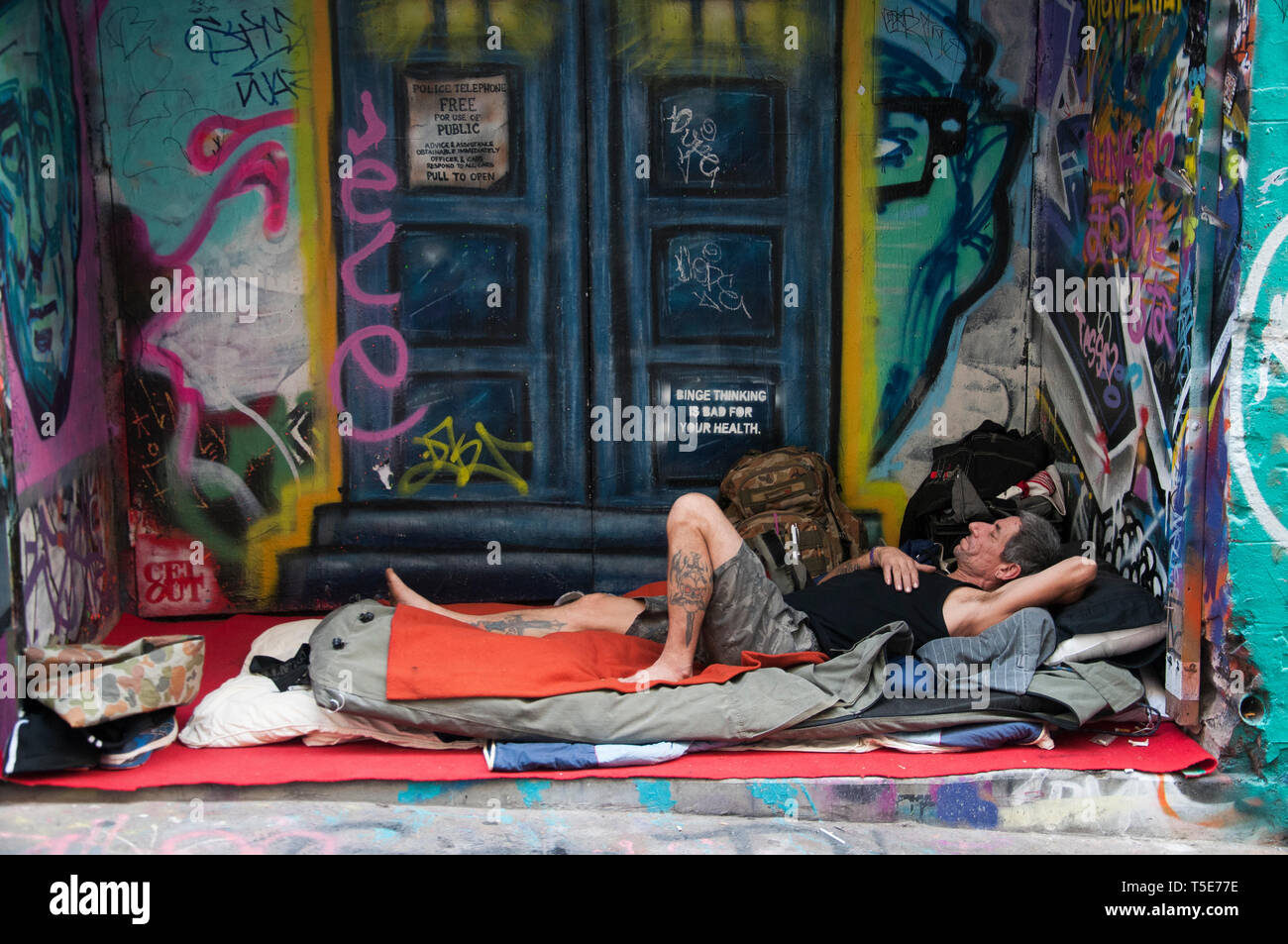 Homeless man oblivious to the street art in Hosier Lane, Melbourne Stock Photo