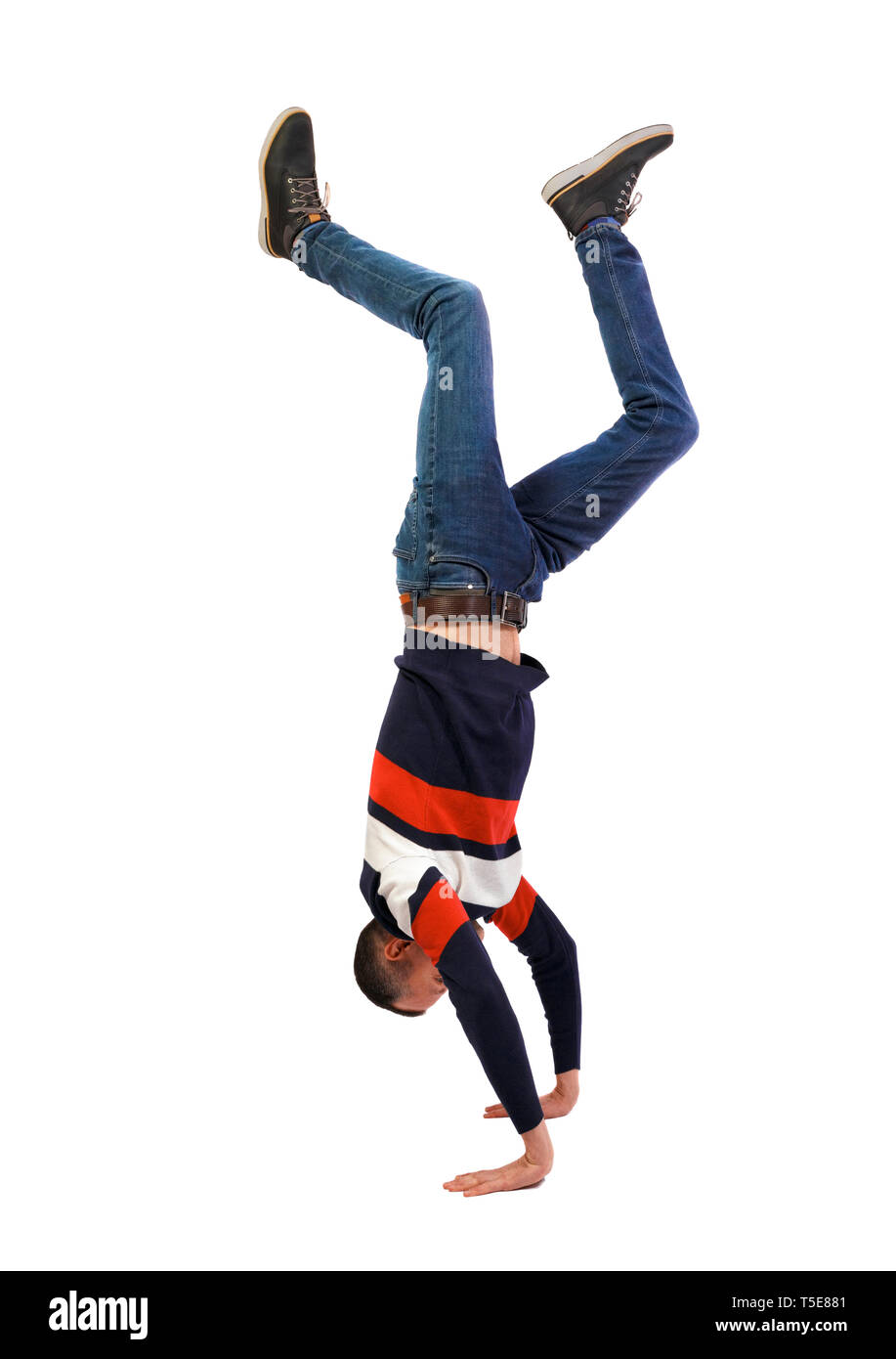 Side view of a man standing on his hands. Stylish guy in a sweater and jeans makes a handstand. backside view of person. Isolated over white backgroun Stock Photo