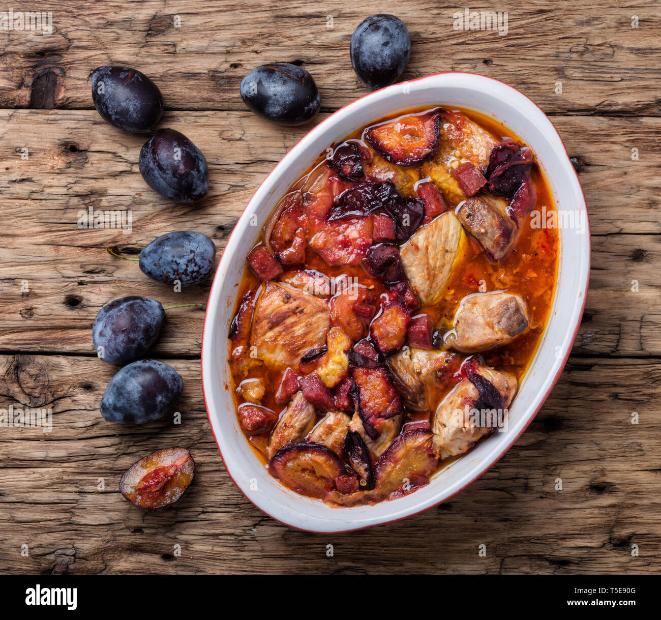 Meat stew with plums on rustic wooden background Stock Photo
