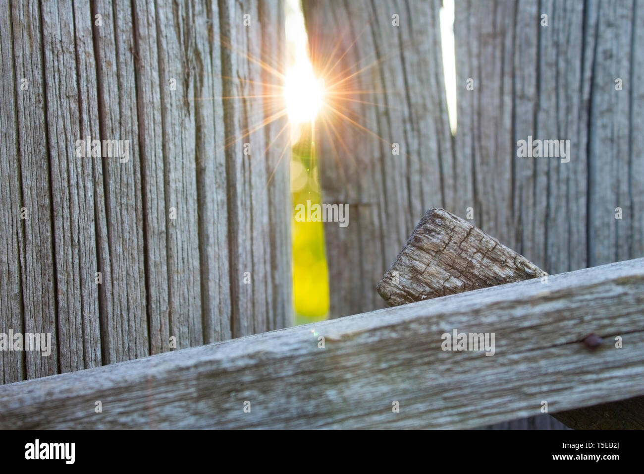 Old wooden fence and a ray of sun in a crack. Close-up with abstract ...