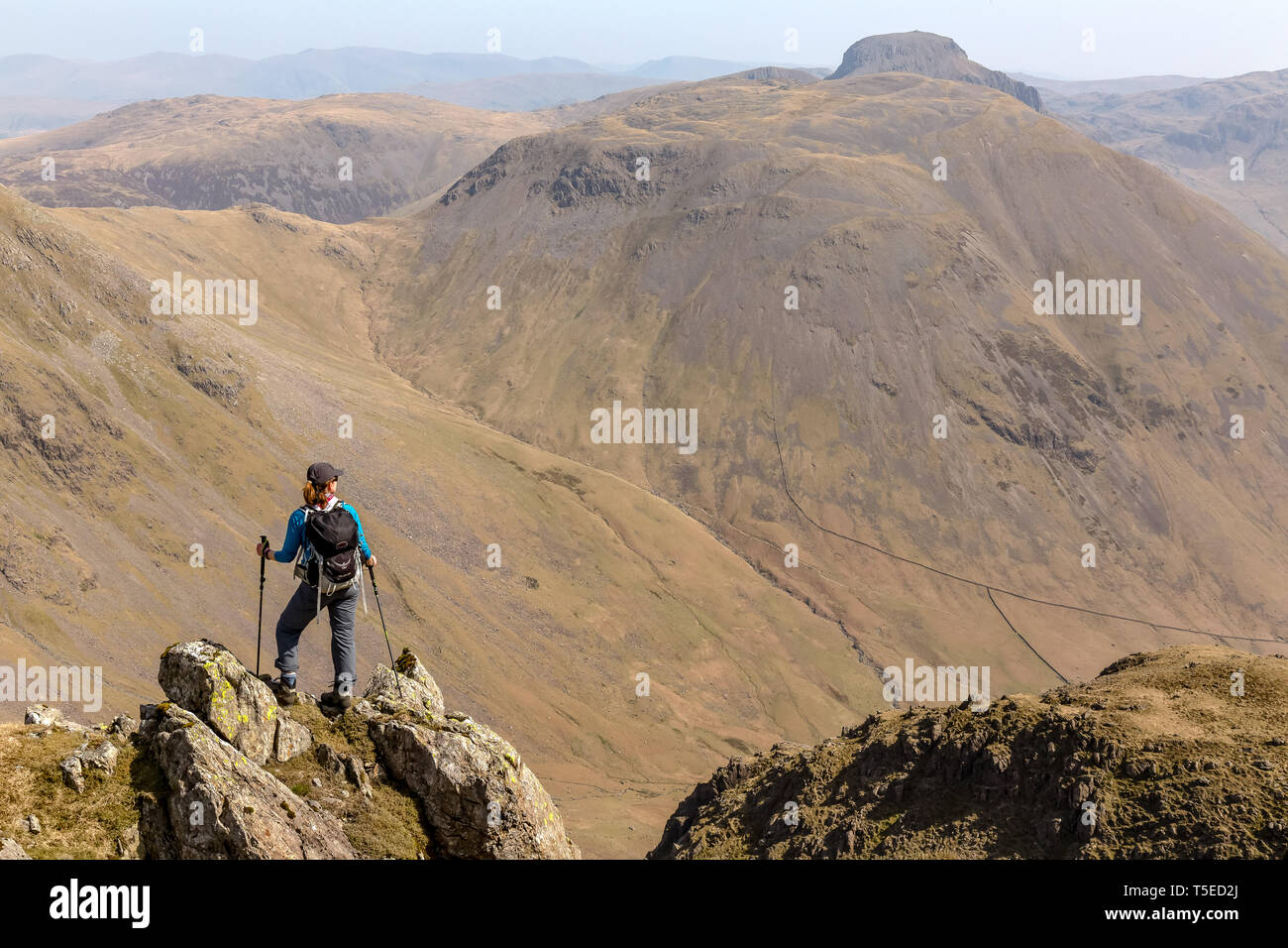 A lone female hiker looking towards the peaks of Kirk Fell and Great Gable, with Black Sail Pass, in the English Lake District National Park. Stock Photo