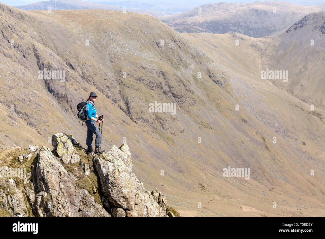 A lone female hiker with  the peaks of Kirk Fell and Great Gable, with Black Sail Pass, in the English Lake District National Park, in the background. Stock Photo