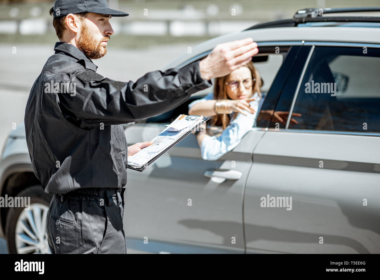 Policeman Showing On The Road Sign While Writing Out Fine For Violation Of Traffic Rules For A 
