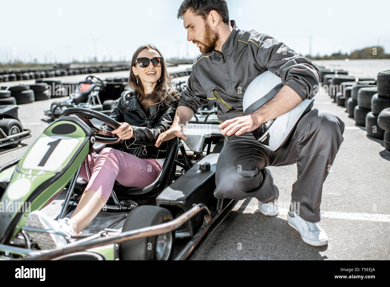 Man In Sportswear Instructing Young Woman Driver Before Racing On