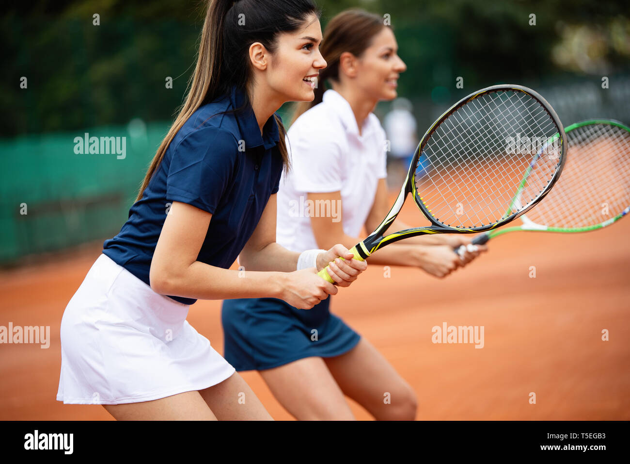 Young happy women friends playing tennis at tennis court Stock Photo