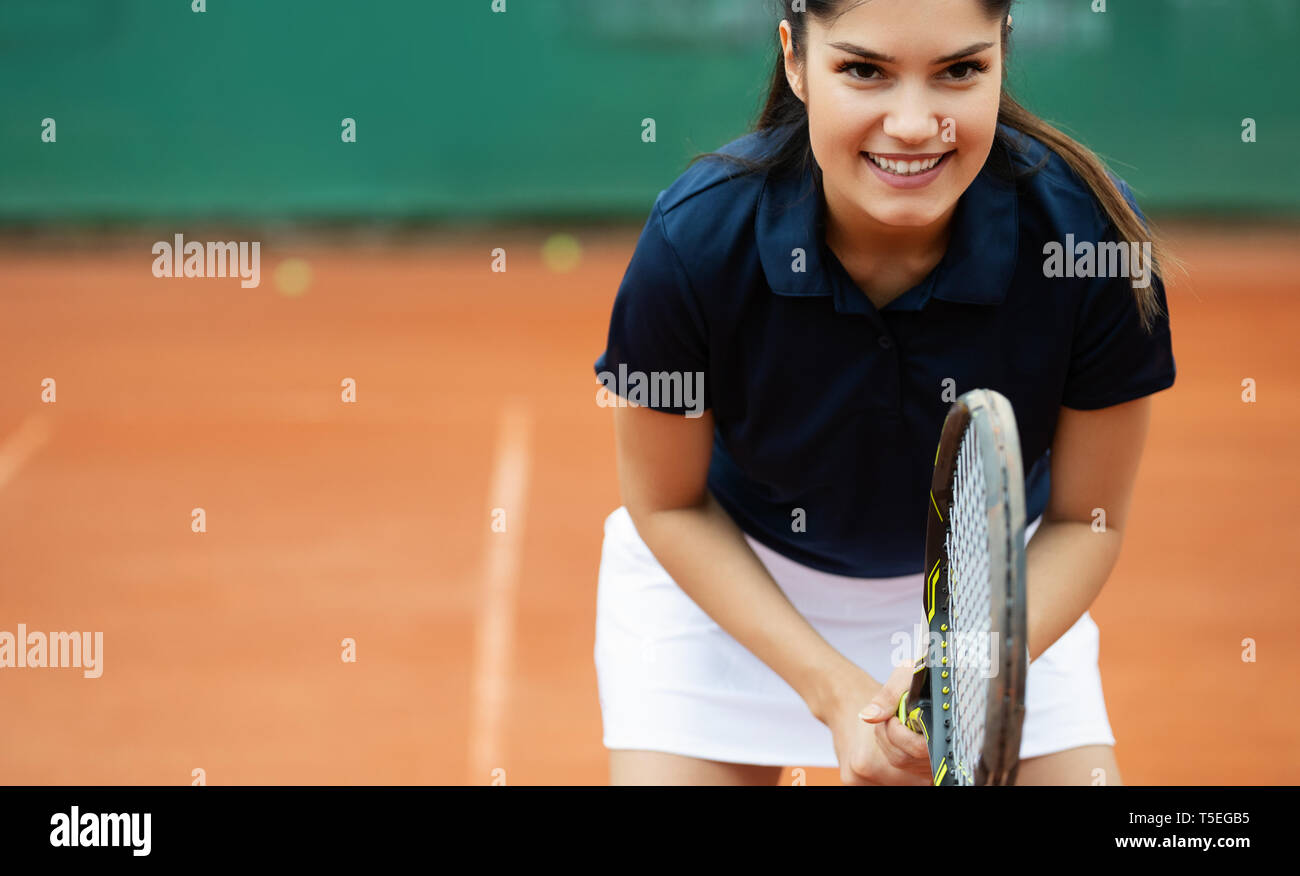 Young happy woman playing tennis at tennis court Stock Photo