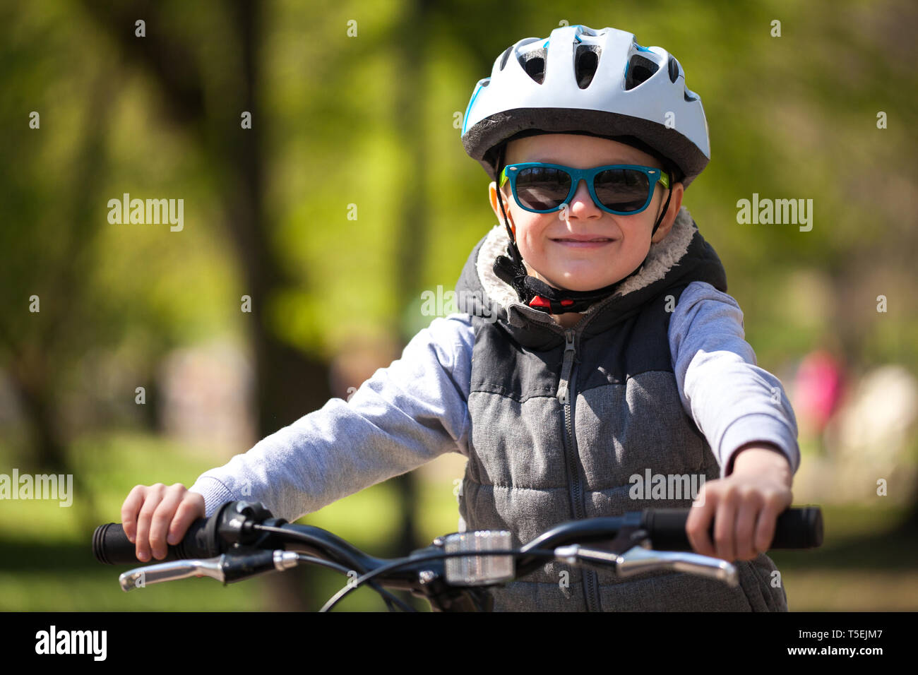 Little boy learns to ride a bike in the park. Cute boy in sunglasses rides  a bike. Happy smiling child in helmet riding a cycling Stock Photo - Alamy