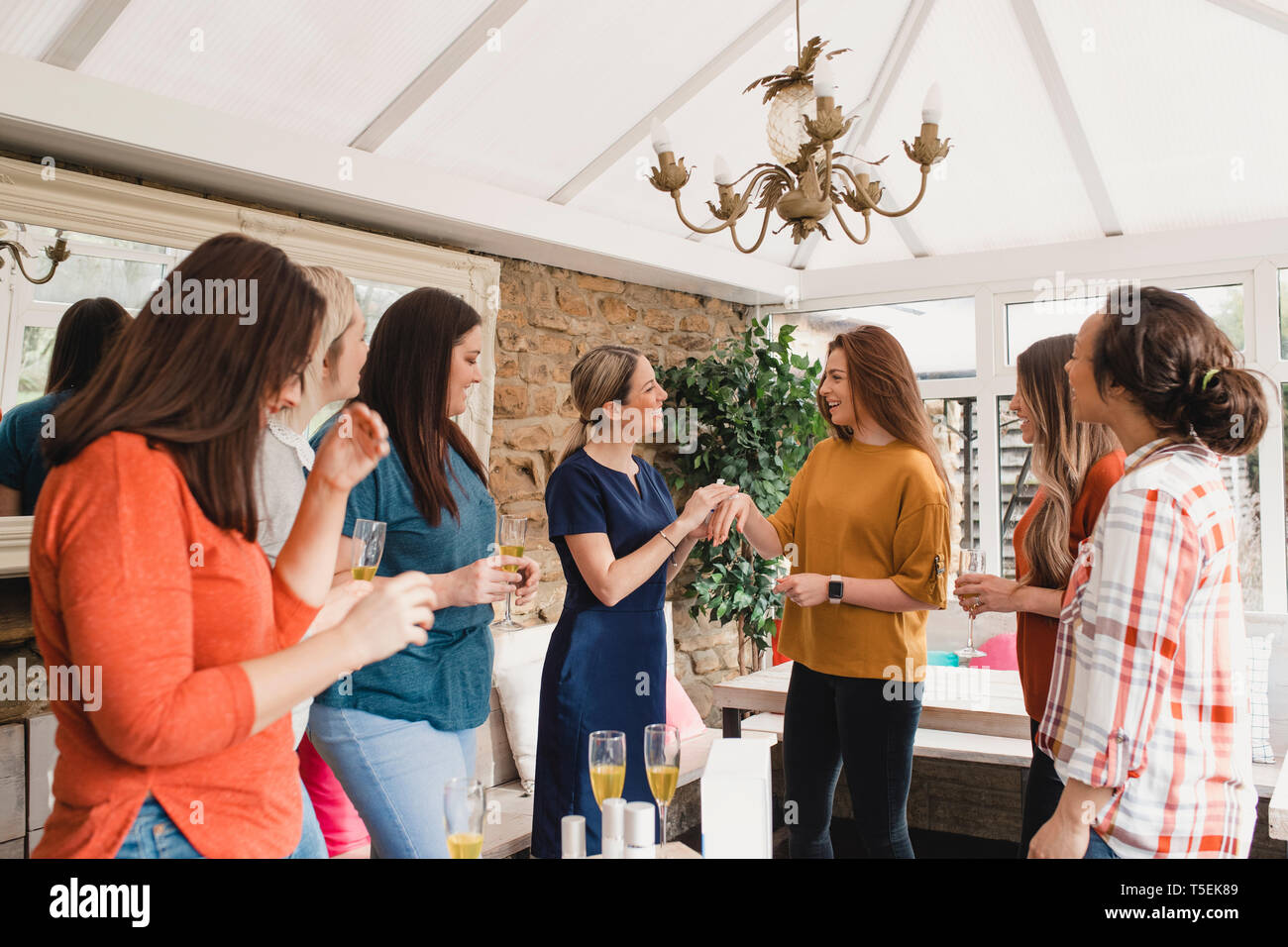 Small group of women with a mixed age range at a beauty product party. The beauty product sales representative is standing talking about the products. Stock Photo