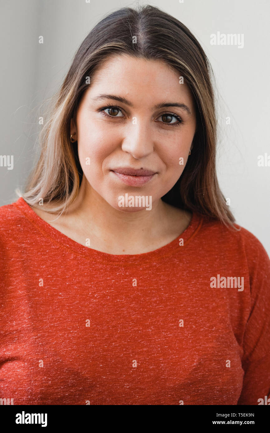 Headshot of a young woman looking at the camera and smiling. She is wearing casual clothing. Stock Photo