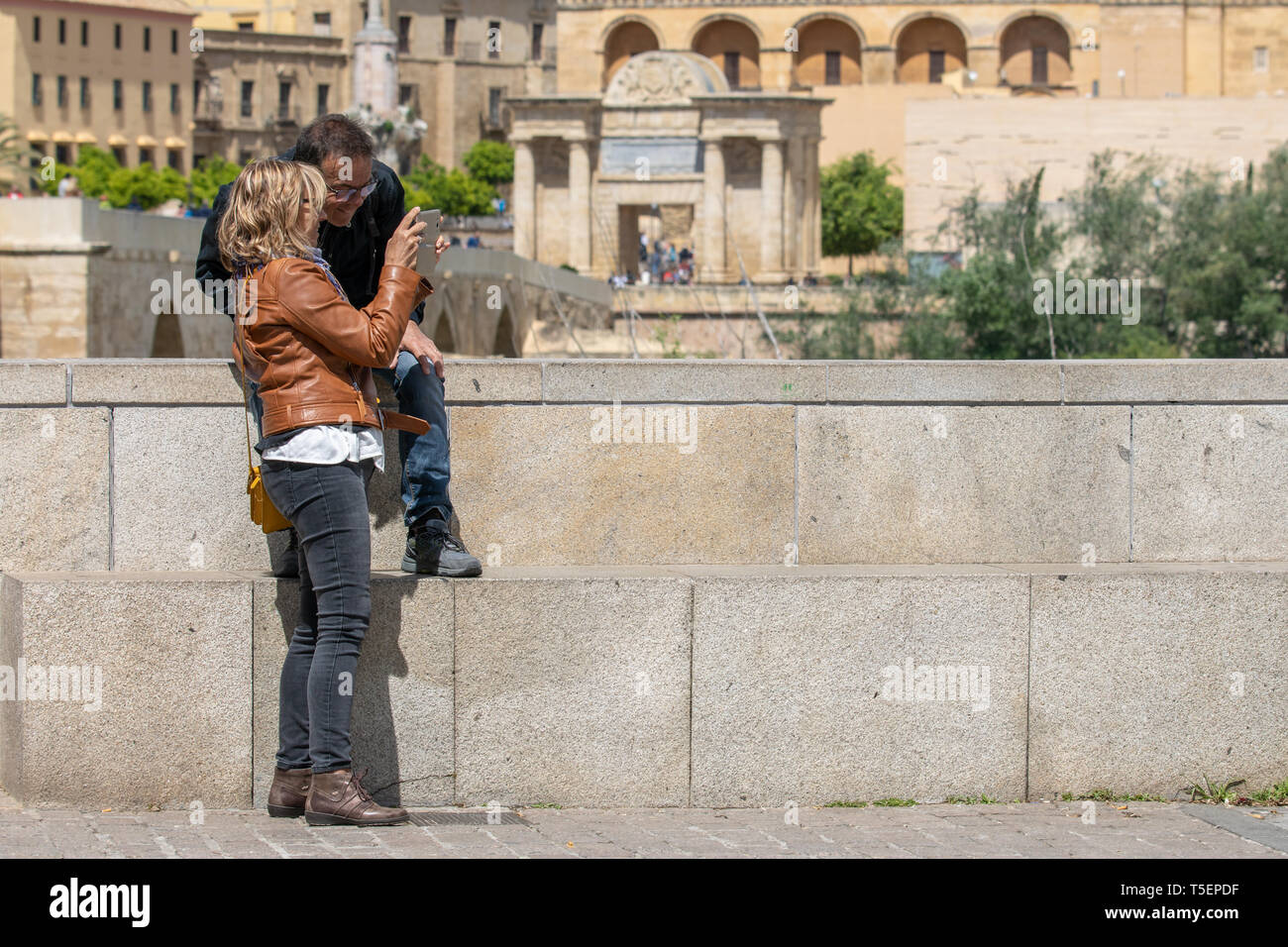 Cordoba, Spain - April 23, 2019: Tourist couple in Cordoba looking photos on their smart phone Stock Photo