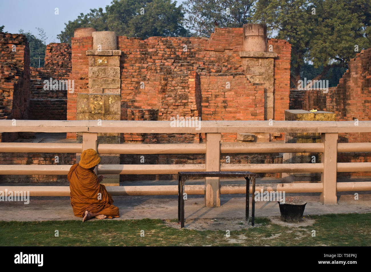 Buddhist monk meditating at the feet of a temple that has been built at the place where Buddha has meditated ( India). Stock Photo