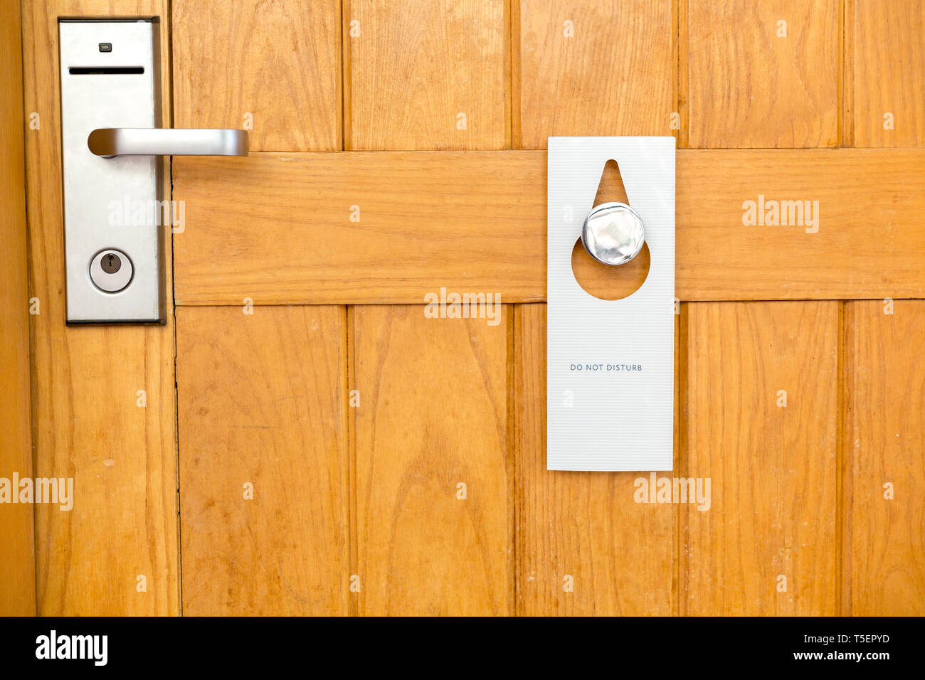 please do not disturb sign on Closed wooden door of hotel room. Stock Photo