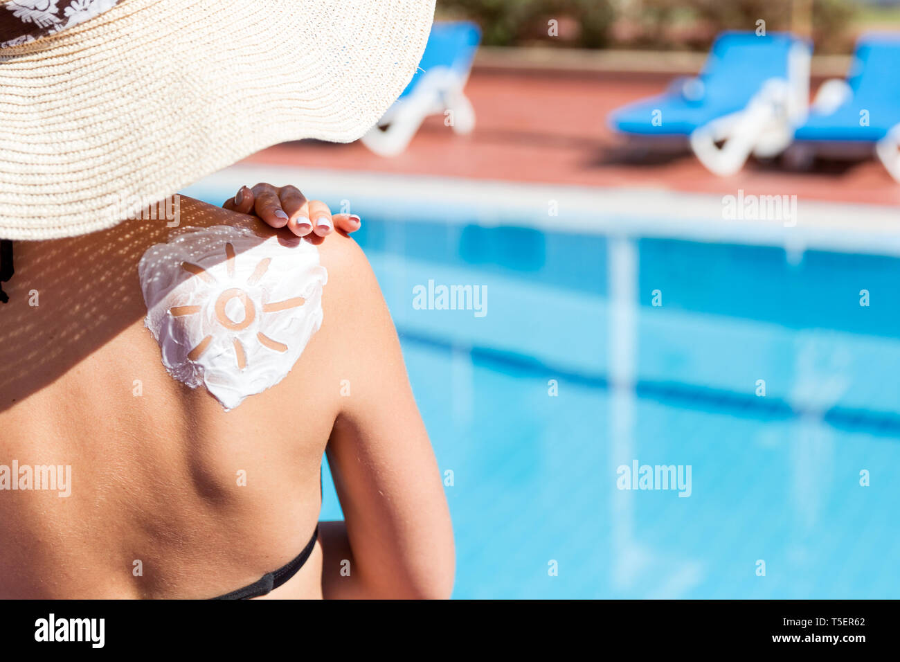 woman has a sun shaped sunblock on her shoulder by the pool
