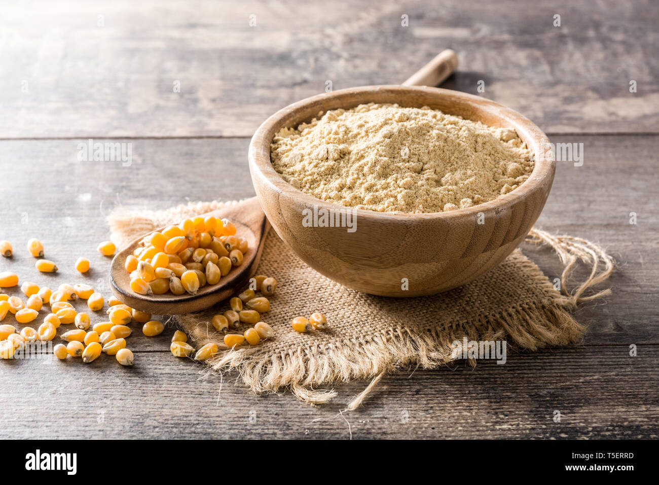 Corn flour in bowl on wooden table Stock Photo