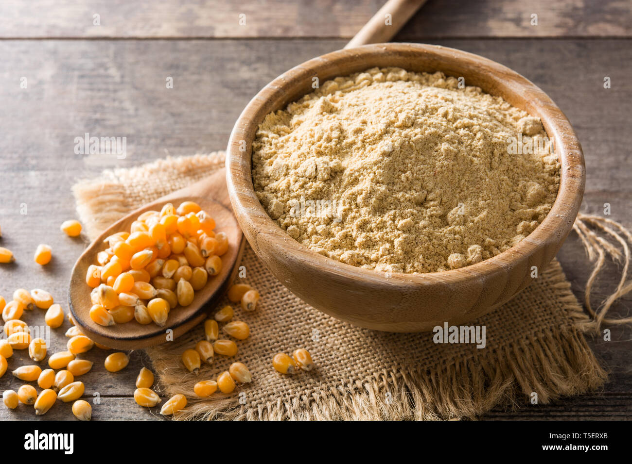 Corn flour in bowl on wooden table Stock Photo