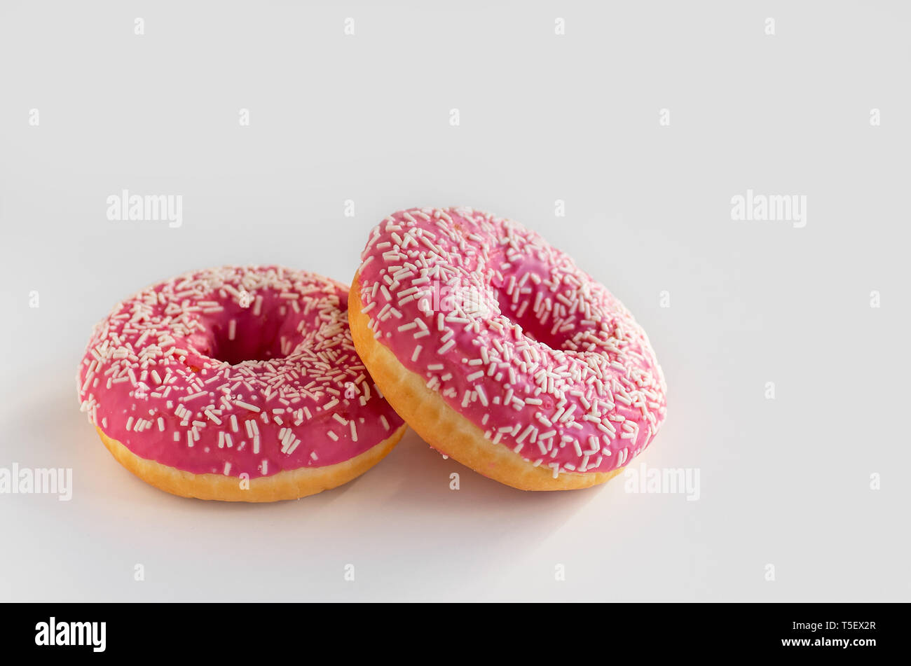 Two donuts with pink icing on a white background. Stock Photo