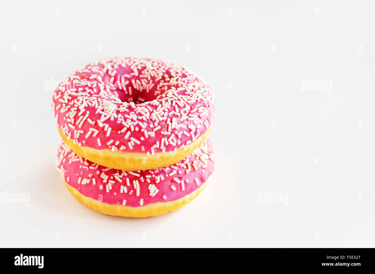 Two donuts with pink icing on a white background. Stock Photo