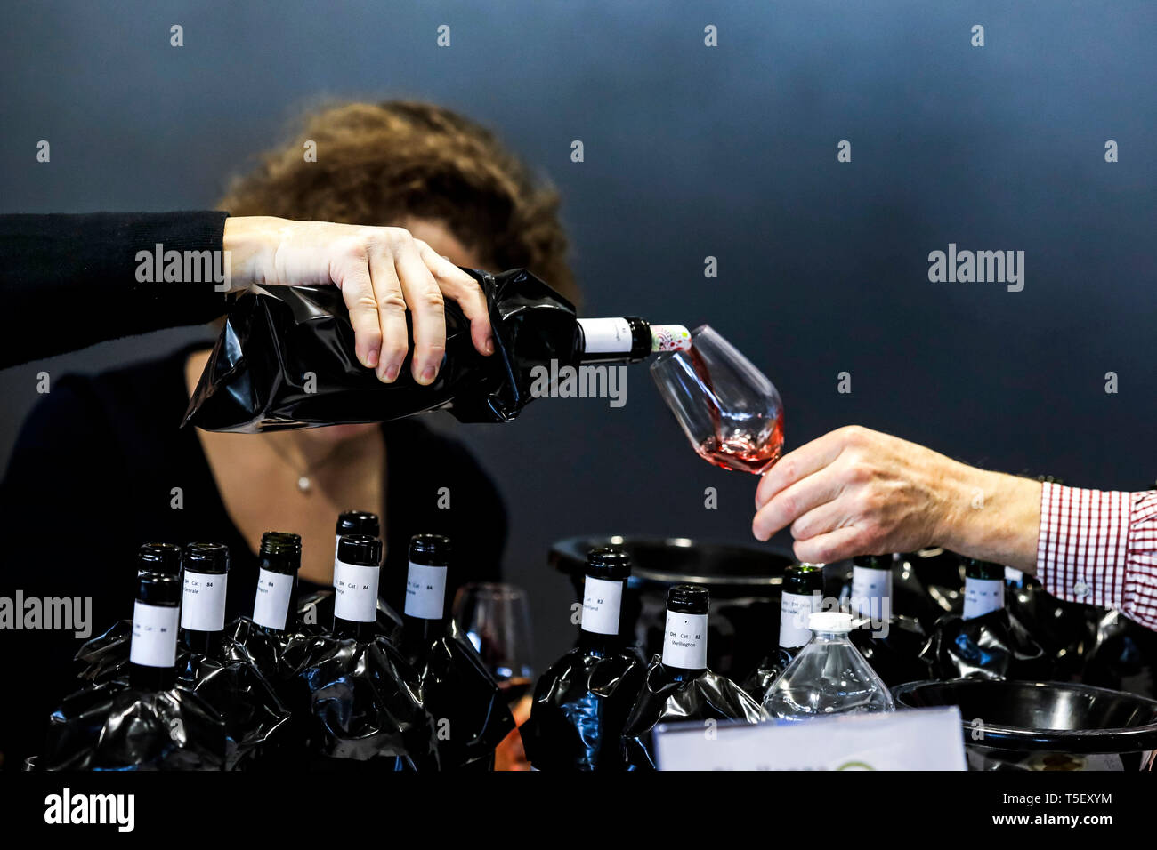 Illustration, blind wine tasting contest: bottle of wine with a sleeve hiding the label and someone pouring some wine in a glass Stock Photo