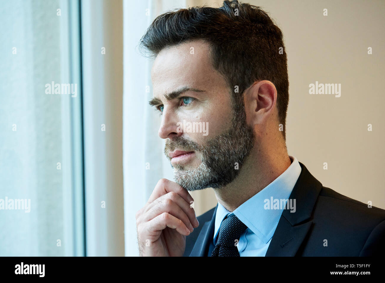 Businessman looking through office window Stock Photo