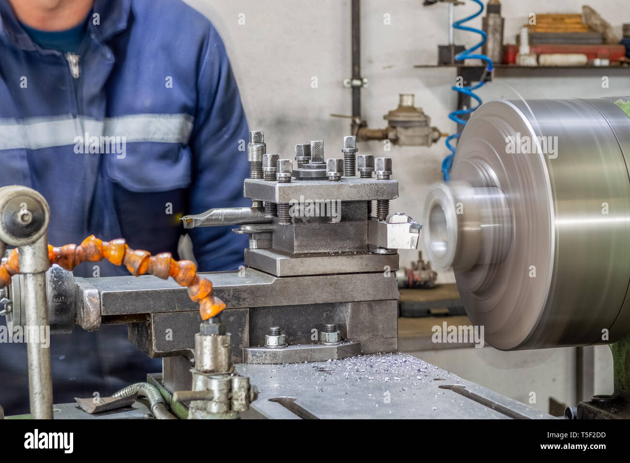Bluecollar machine operator working with lathe machine in a factory