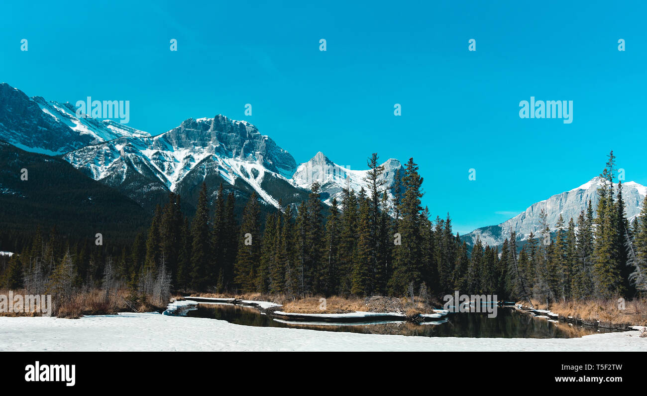 Wide Panoramic Landscape of Snowcapped Mountain Peaks and Bow River Valley in Alberta Foothills of Canadian Rockies near Banff National Park Stock Photo
