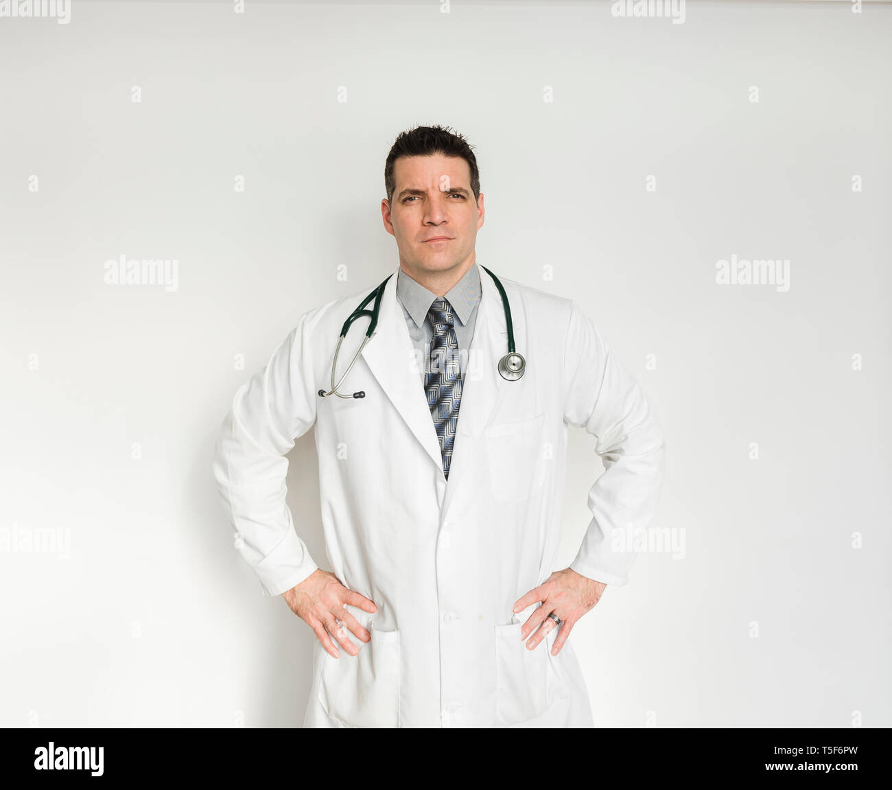 Medical doctor in lab coat standing with hands on hips. Stock Photo