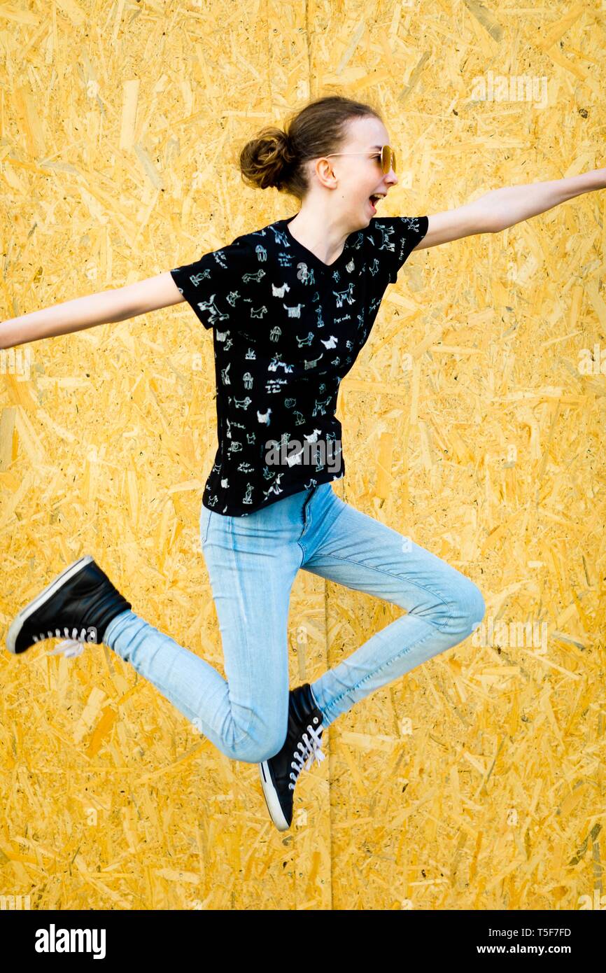 Young teenaged slim girl jumping in front of fence from wooden mdf
