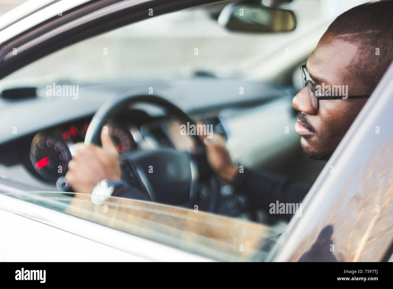 A young businessman in a suit sits at the wheel of a expensive car. Stock Photo