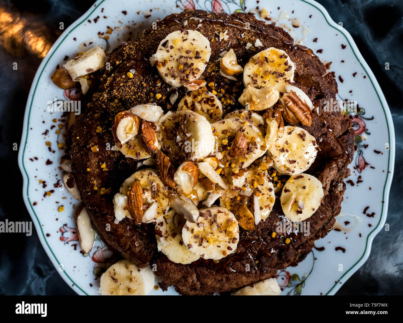 Cacao pancakes covered in banana, nuts and honey Stock Photo