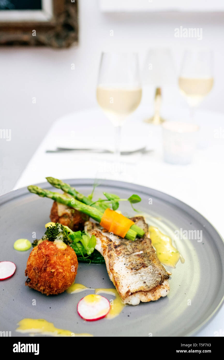 Colourful shot of fish and vegetable dish at a restaurant with wine Stock Photo