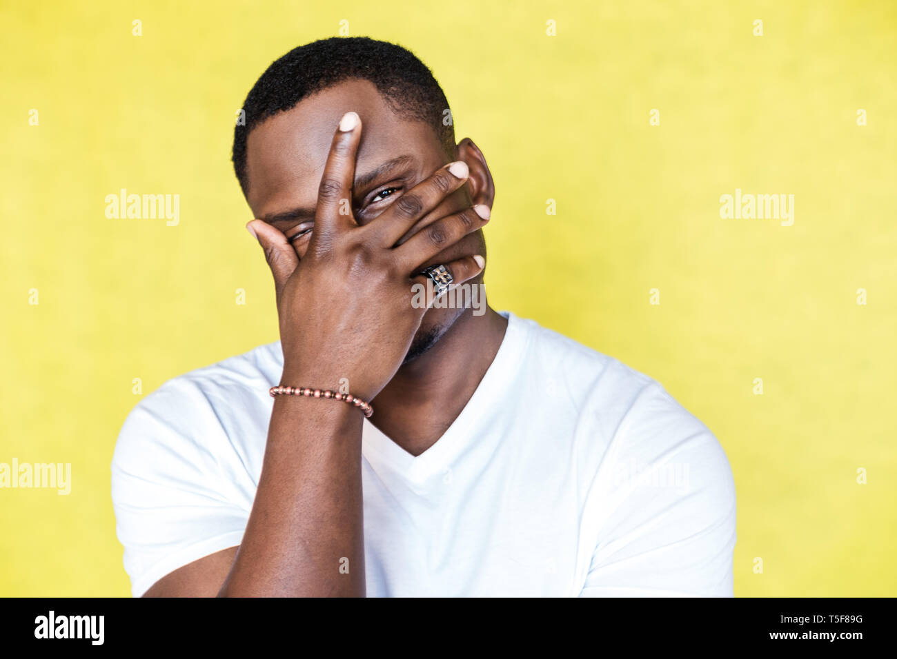 African American man covering face with hand and looking at camera ...