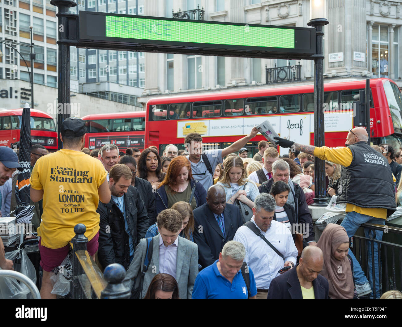 Vendors distribute copies of Evening Standard newspaper at rush hour to commuters crowding into Oxford Circus underground station in London Stock Photo