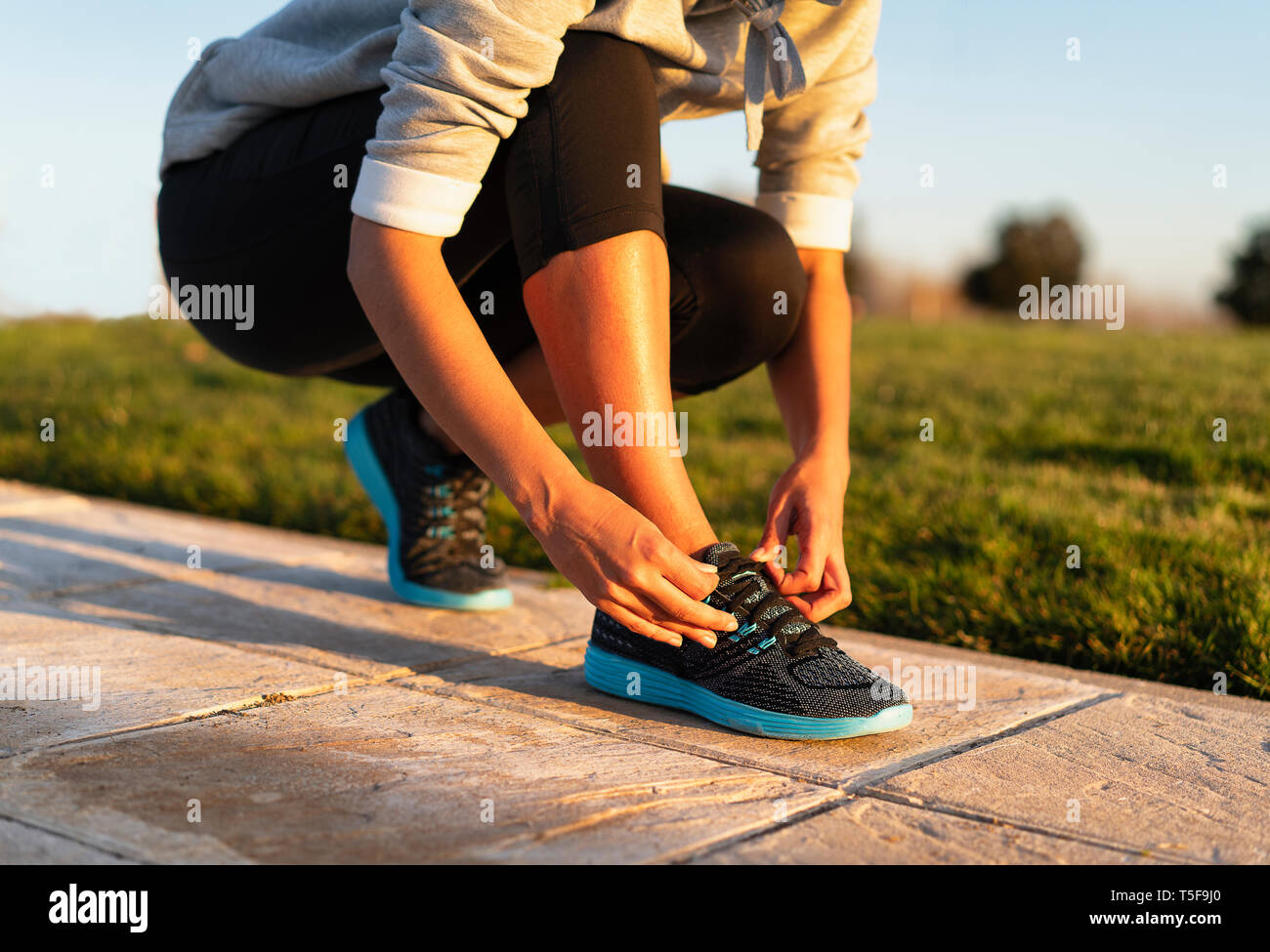Young woman tying shoelace of sneakers to make outwork training running.  Fitness and healthy lifestyle Stock Photo - Alamy