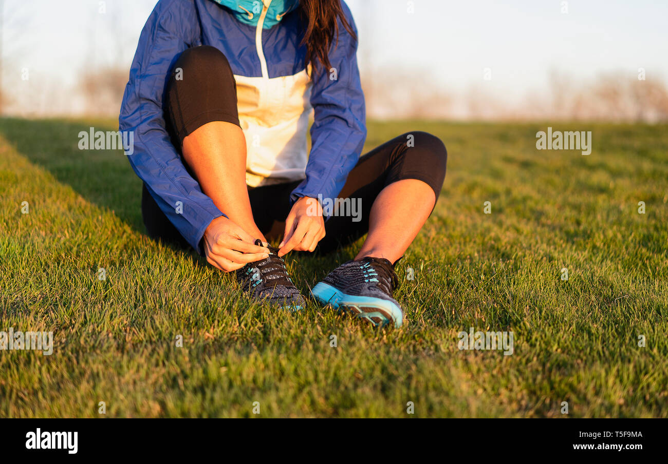 Young woman tying shoelace of sneakers to make outwork training running. Fitness and healthy lifestyle Stock Photo