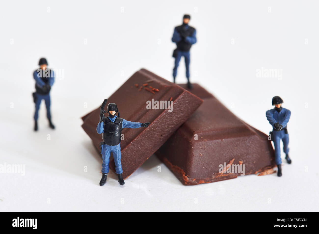 Figurines representing police officers surrounding pieces of chocolate: protection and securing of the global chocolate market *** Local Caption *** Stock Photo