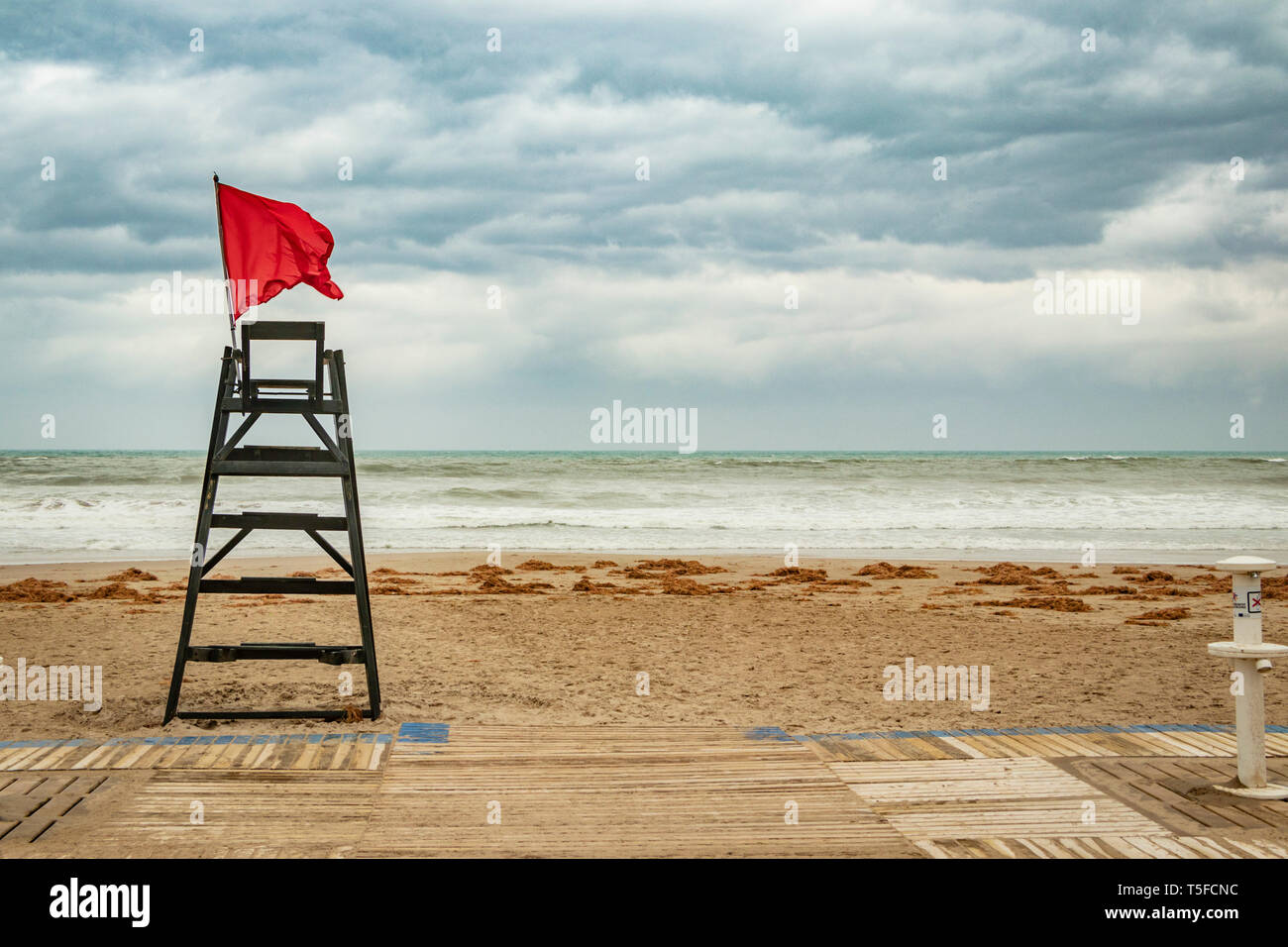 red flag flying from life guard chair during storm by the beach in Alicante Spain Stock Photo