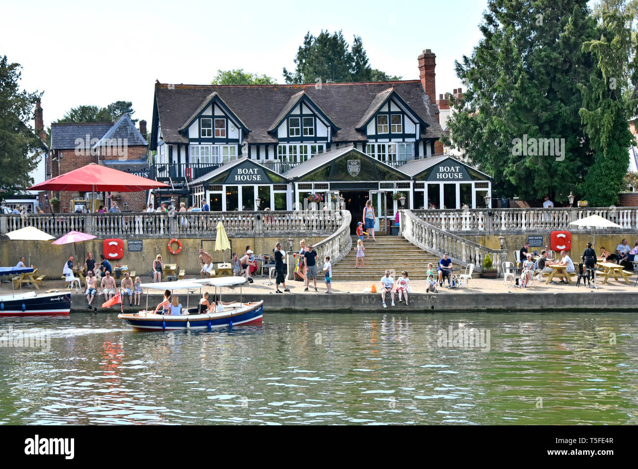 People enjoying refreshments & boat hire on hot summer day at riverside Boat House pub business on River Thames Wallingford Oxfordshire England UK Stock Photo