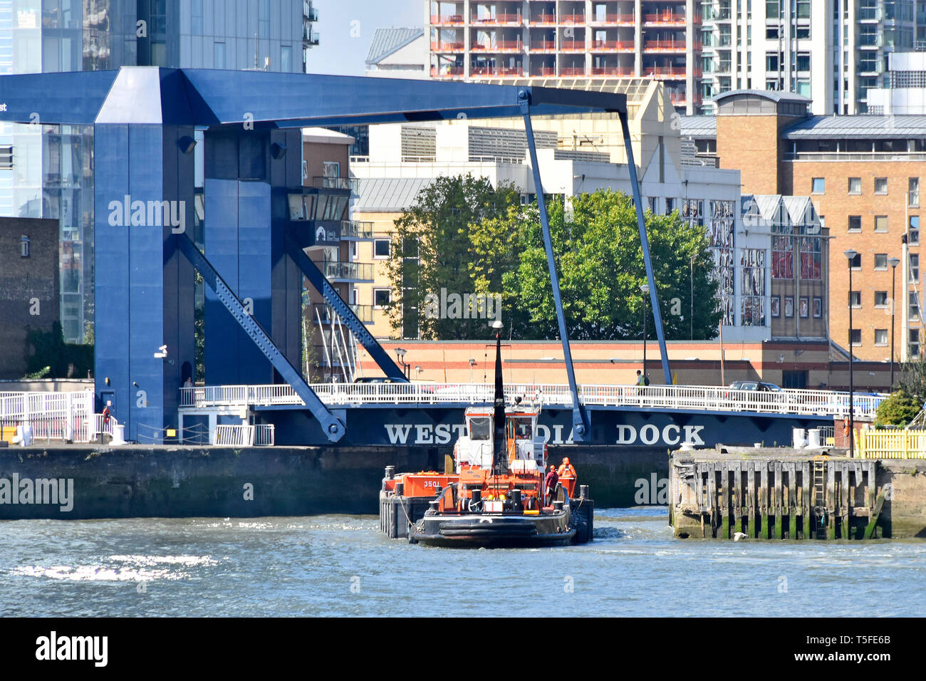 River Thames & modern road bridge entrance for tug boat & barge into South Dock of West India Docks access to Canary Wharf estate London Docklands UK Stock Photo