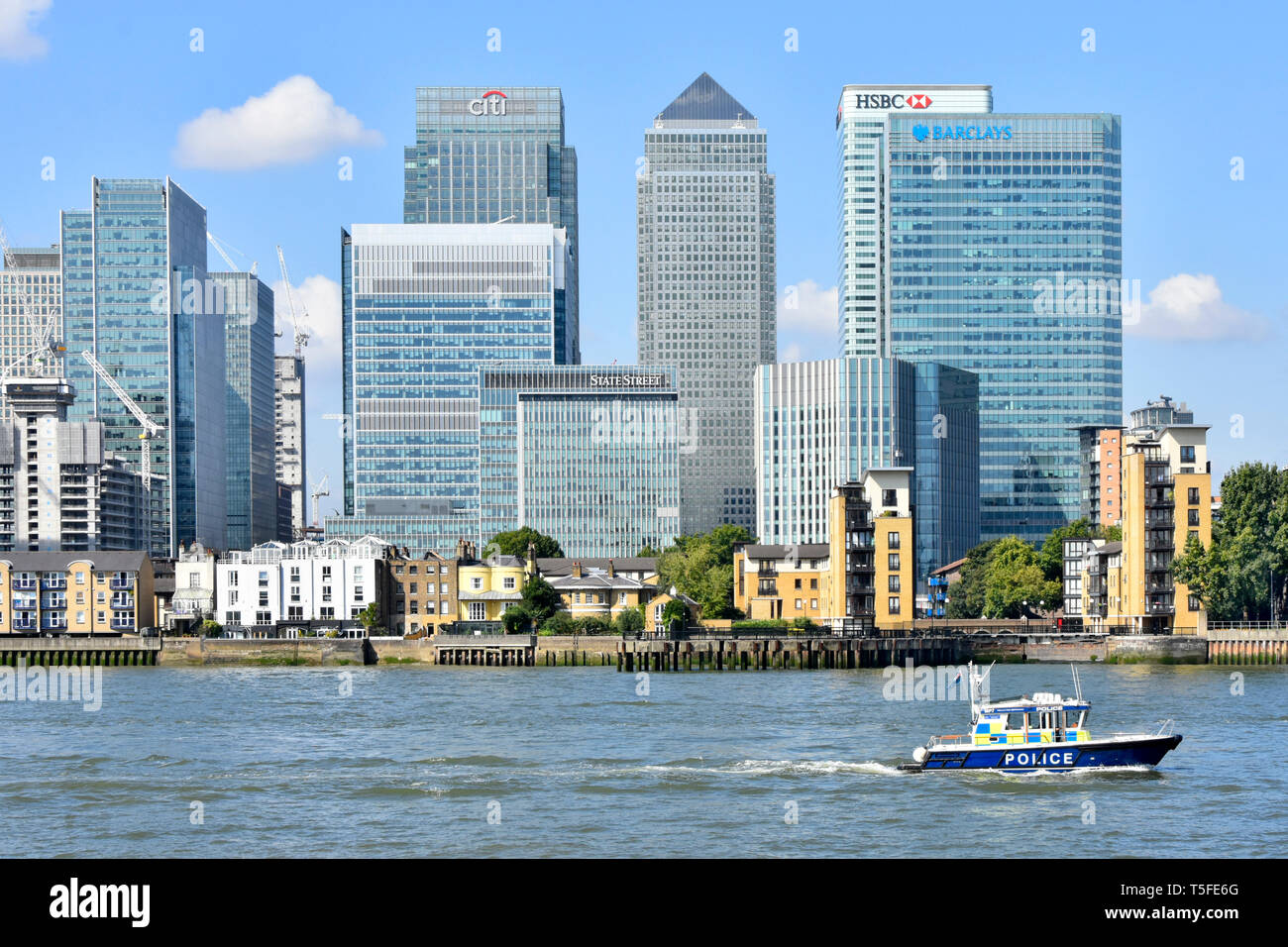 Metropolitan police River Thames patrol boat & modern landmark skyscraper bank buildings on Canary Wharf skyline Isle of Dogs East London Docklands UK Stock Photo