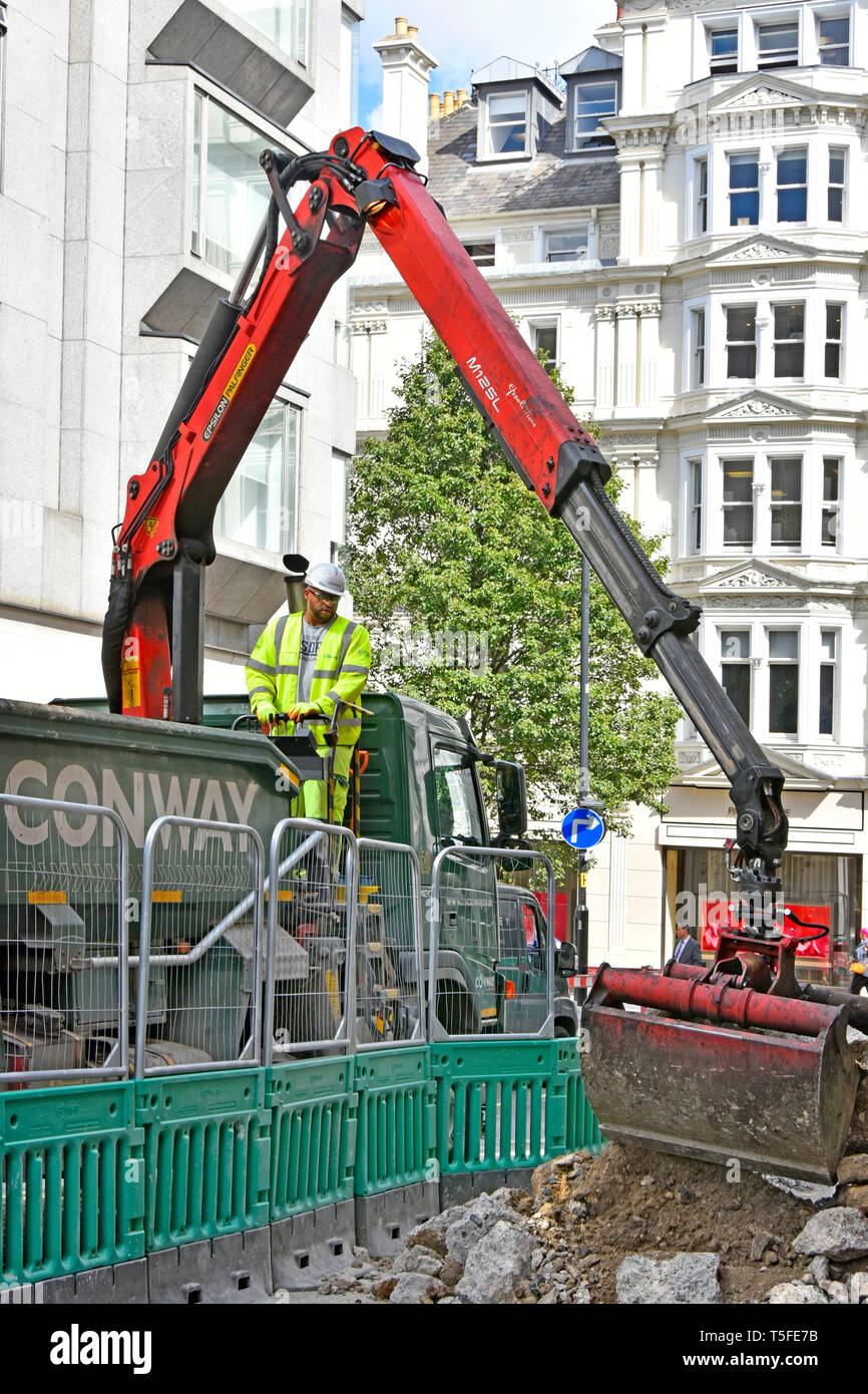 Conway contractor business tipper lorry truck driver loading debris from road & street works excavation with hydraulic grab crane London England UK Stock Photo